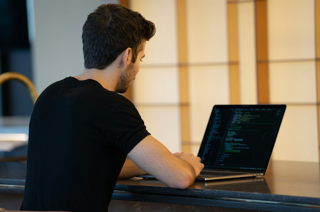 person writing code on laptop